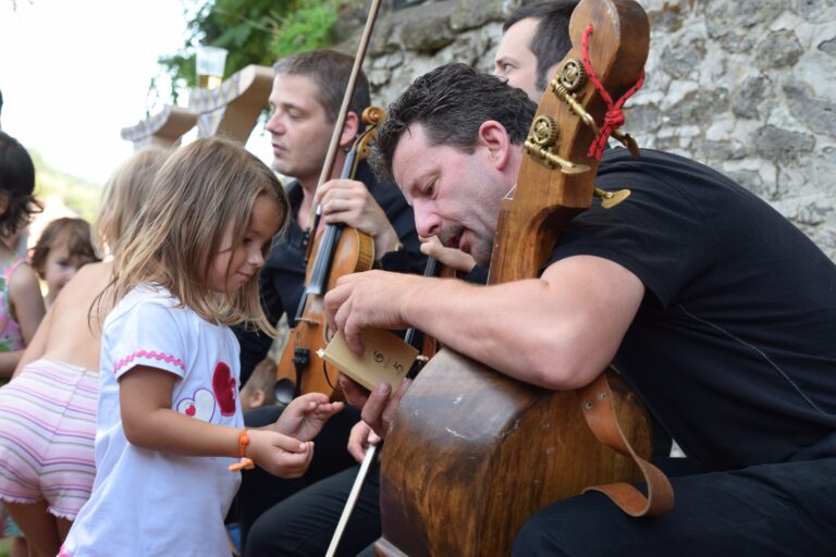 Cellist showing little girl how to play CREDIT HontAngela
